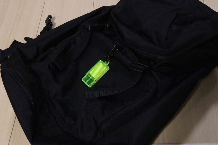 黒いリュックサックのポケット部分に反射材付きミニホイッスルが取り付けられている
