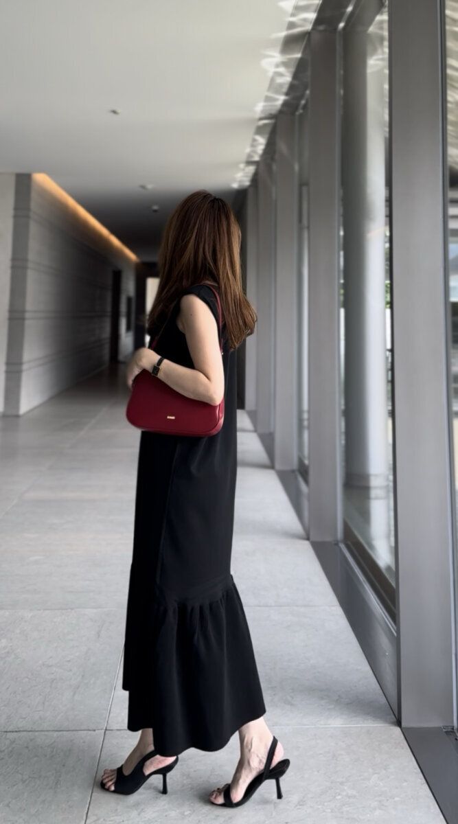 黒いノースリーブワンピースの女性が廊下を歩く後ろ姿
