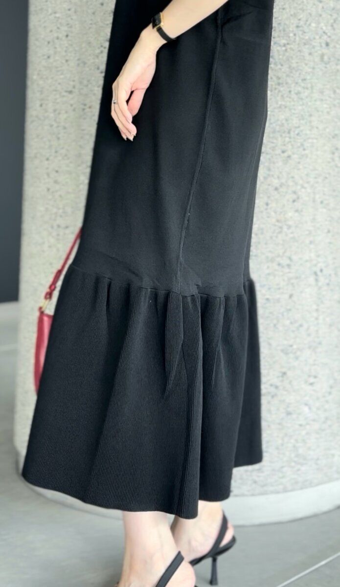 黒いワンピースの裾フレアとヒールサンダルを履いた足元