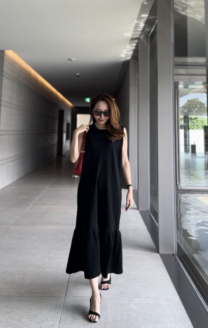 黒いノースリーブワンピースの女性が廊下を歩く全身