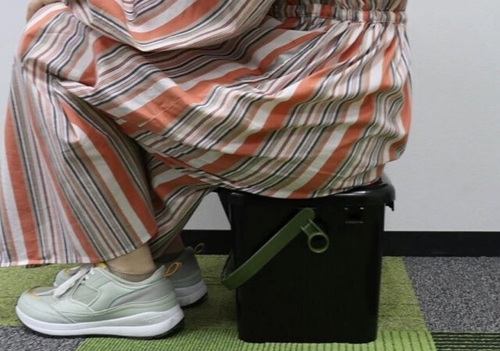 ストライプのパンツを履いた女性が黒い座れるボックスに座っている