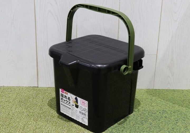 黒い座れるボックスが緑の取っ手を上にして置かれている