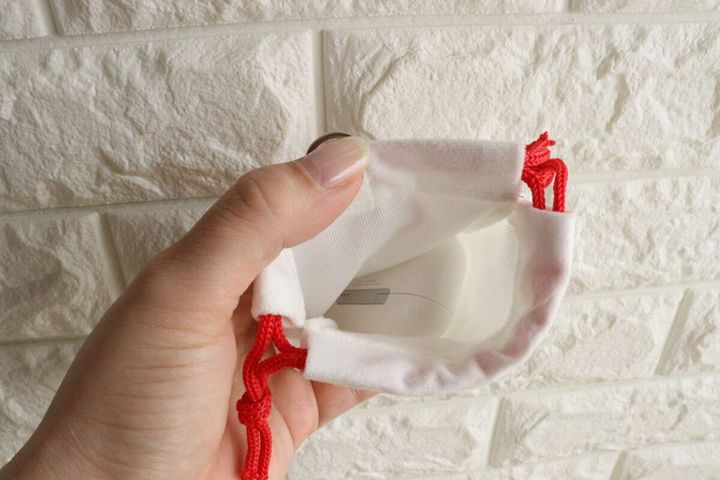 女性の手が白い巾着袋の中にAirPodsケースを入れている