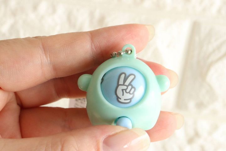 女性の指が水色のじゃんけんキーホルダーを持ちチョキが出ている