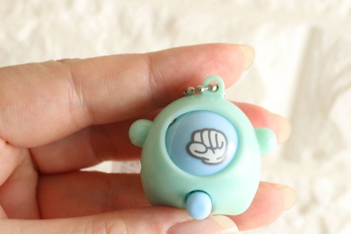女性の指が水色のじゃんけんキーホルダーを持ちグーが出ている