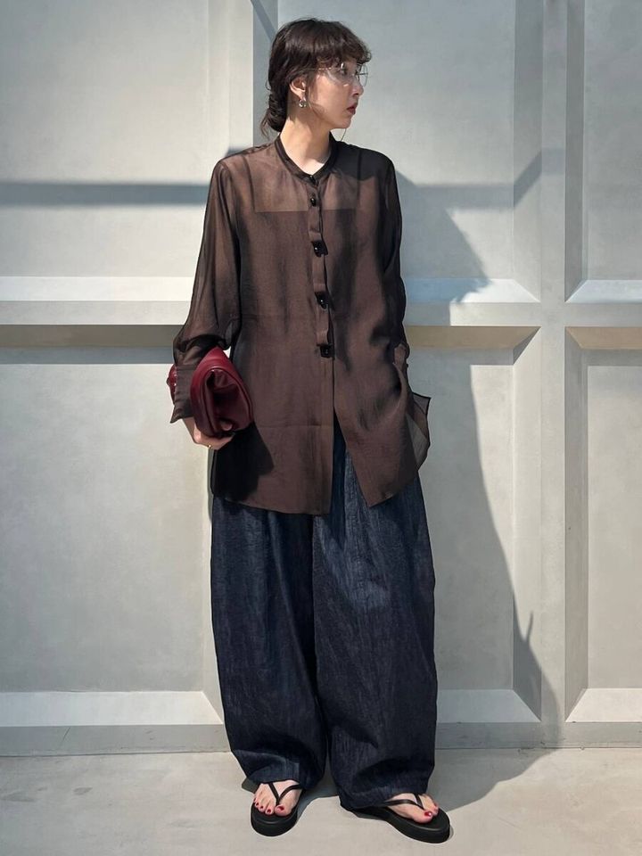 ダークブラウンのシアーシャツとデニムを着た女性