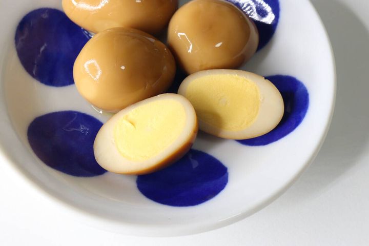 白い皿に盛られた半分にカットされたおでんのたまごと丸ごとのたまご