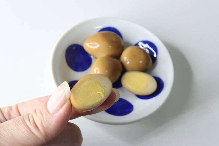 女性の指が半分にカットされたおでんのたまごを持つ