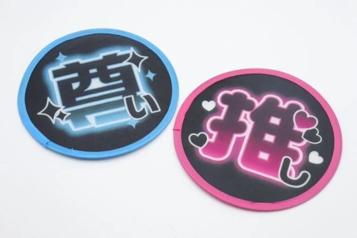 「尊い」と「推し」の文字が書かれた広げた状態の丸うちわ