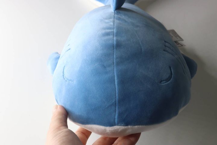 手が青いサメクッションのお腹部分を握っている