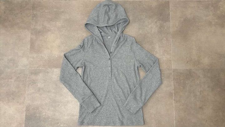 グレーのフーデッドリブTシャツが床に平置きされている