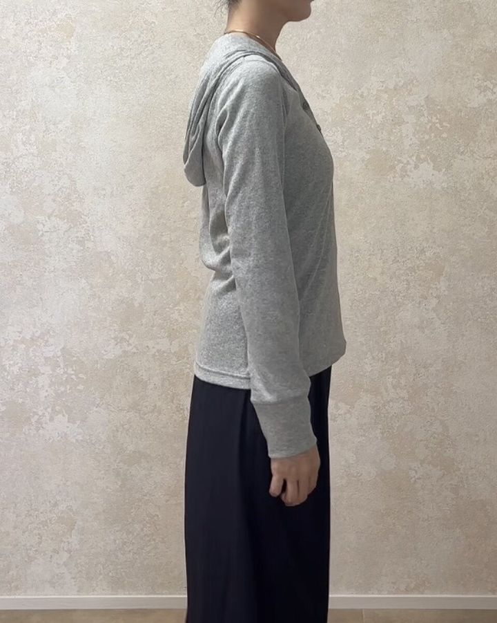 グレーのフーデッドリブTシャツと黒いワイドパンツを着用した女性の横向き