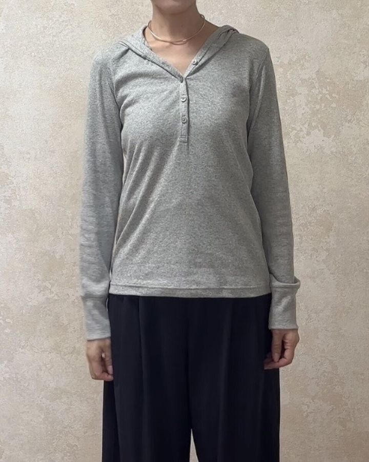 グレーのフーデッドリブTシャツと黒いワイドパンツを着用した女性の全身