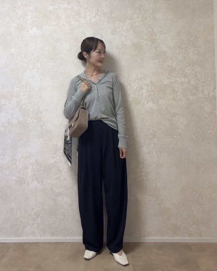 グレーのフーデッドリブTシャツと黒いワイドパンツ、白靴を着用した女性