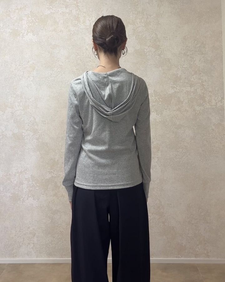 グレーのフーデッドリブTシャツと黒いワイドパンツを着用した女性の後ろ姿