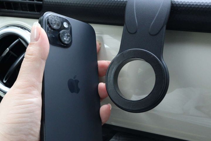 女性がiPhoneをスマホスタンドのマグネット部分に近づけている