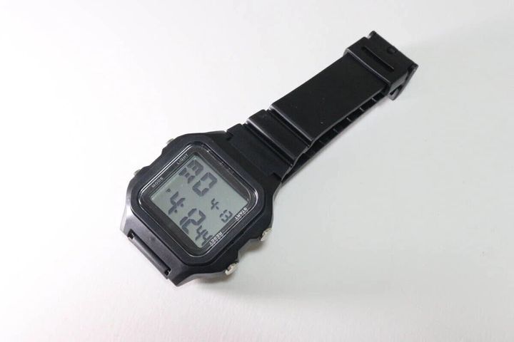 白い背景に置かれた黒いスクエア型デジタルウォッチ。時刻は4時12分を表示。