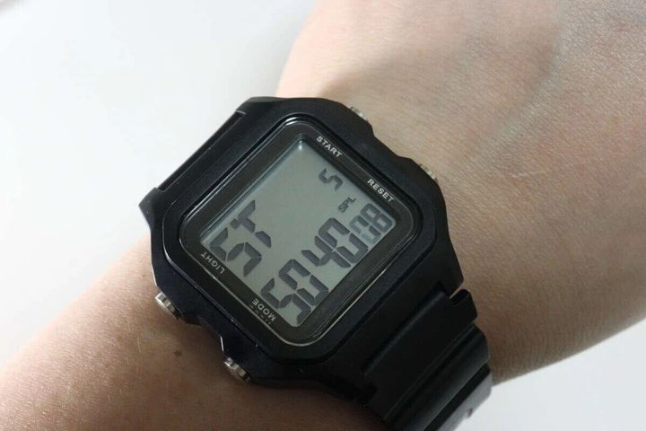 左腕に装着された黒いスクエア型デジタルウォッチ。時刻は6時47分を表示。