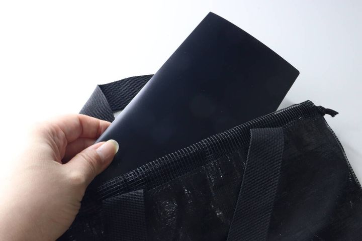 女性が黒いチケットファイルを黒いバッグのポケットに入れている