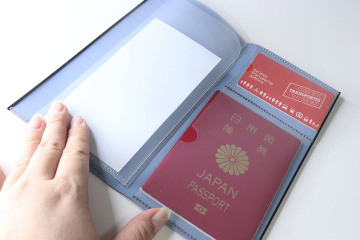開いたチケットファイルにパスポートと赤いカードが収納されている