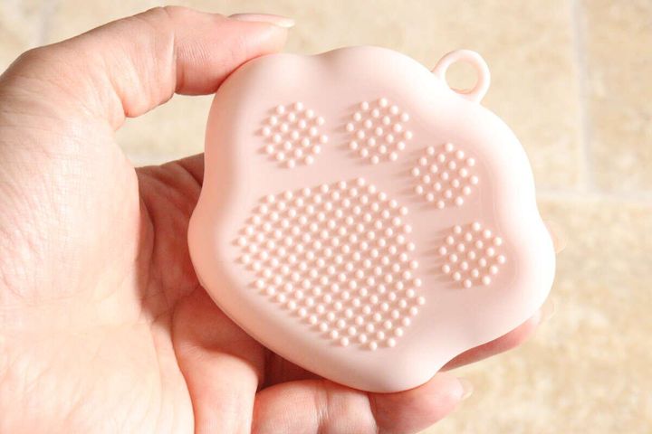 女性の手のひらに乗せられたピンクのパフケース裏側の凹凸
