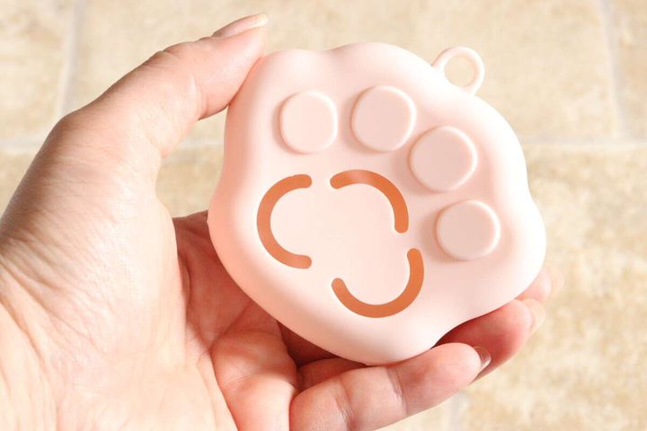 女性の手のひらに乗せられたピンクの肉球型パフケース表側
