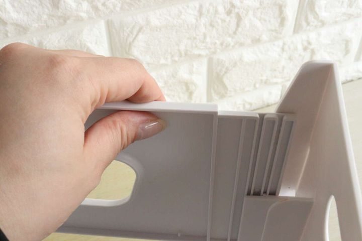 白いファイルスタンドのパーツを溝にはめ込んでいる手元
