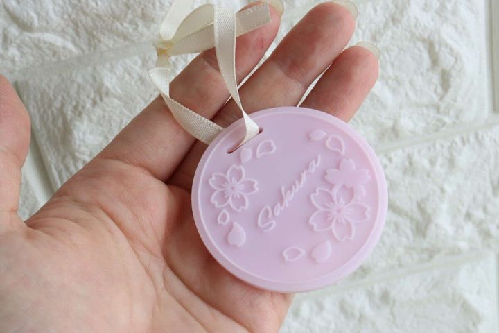 手のひらに乗せられた、リボン付きのピンク色の桜柄ラバーサシェ