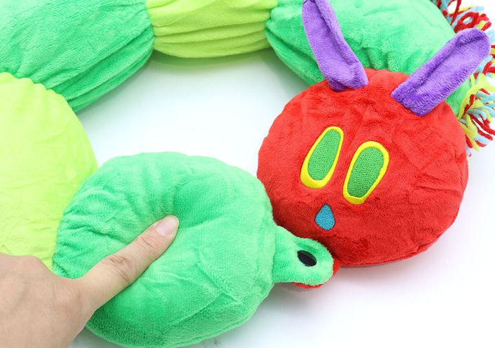 はらぺこあおむしネックピローの柔らかさを指で押して確認している