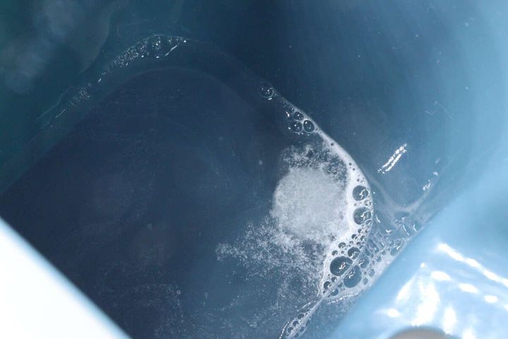 青いバケツの水にタブレットクリーナーが溶け始める