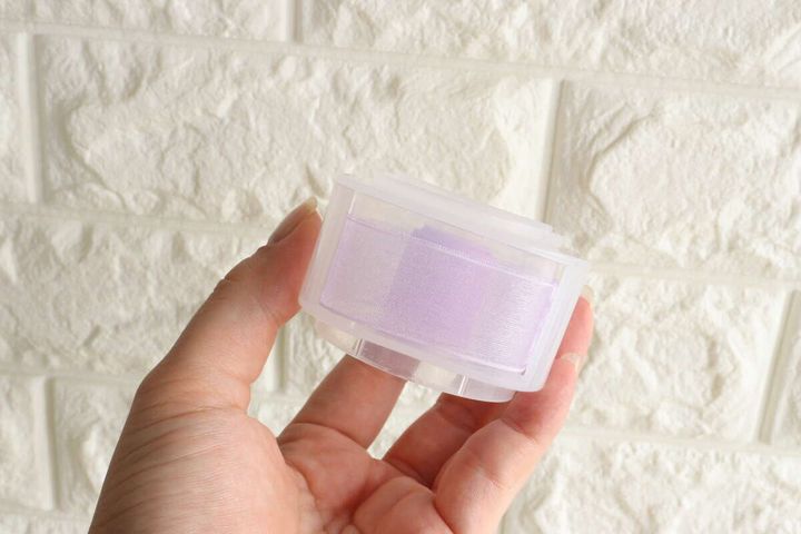 薄紫色のリボンが巻かれたリボンホルダーを手に持っている