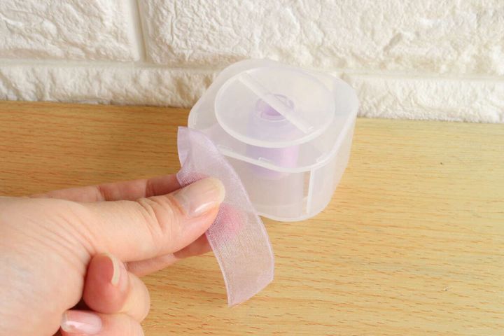 リボンホルダーのスリットから薄紫色のリボンを引き出している手元