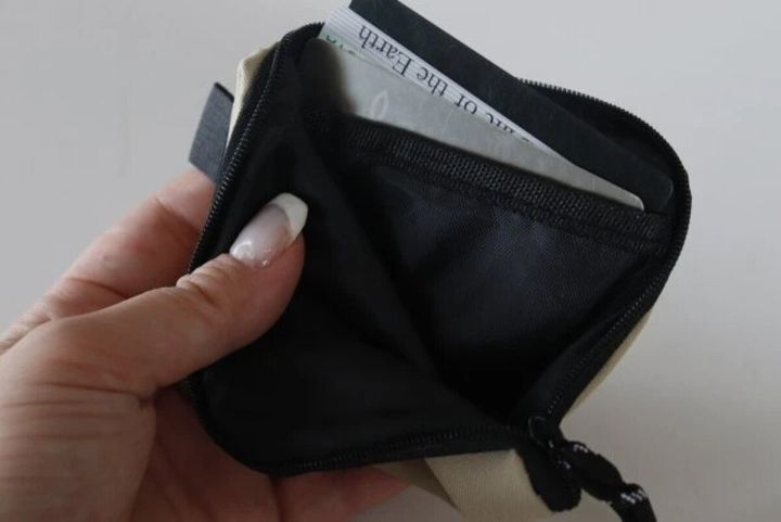 女性の指がベージュ色のコインケースを開き、中にカードが入っている様子
