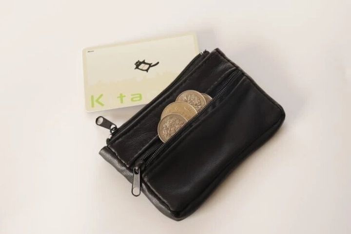 黒い本革小銭入れと、その奥にカードが置かれている。小銭入れには硬貨が見える