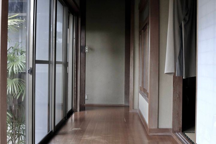 薄暗い古い廊下。外の景色と部屋の内装が見えている。
