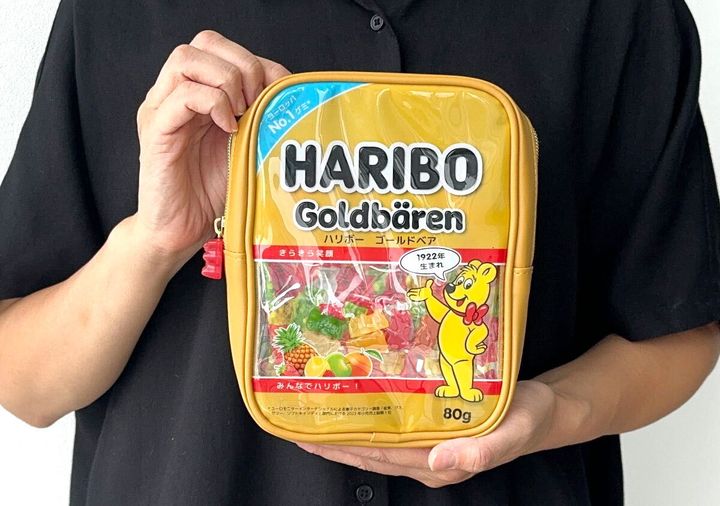 黒い服の人がHARIBOゴールドベアのポーチを両手で持っている