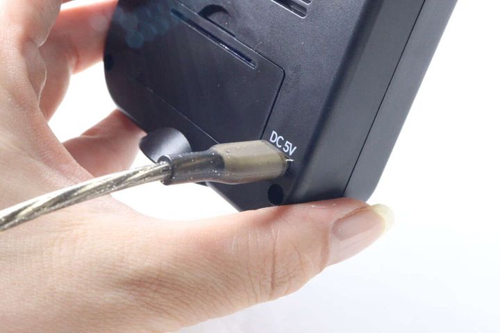 女性がデジタル時計の側面にUSB Type-Cケーブルを接続している