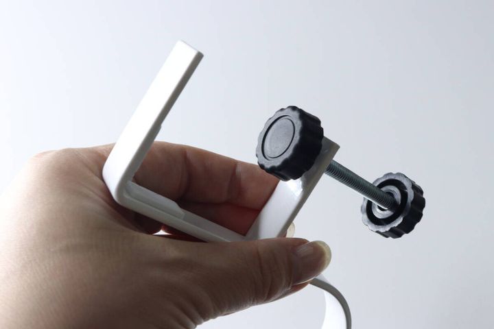 手が白いフック本体と黒いネジ部品を分解している様子をクローズアップ