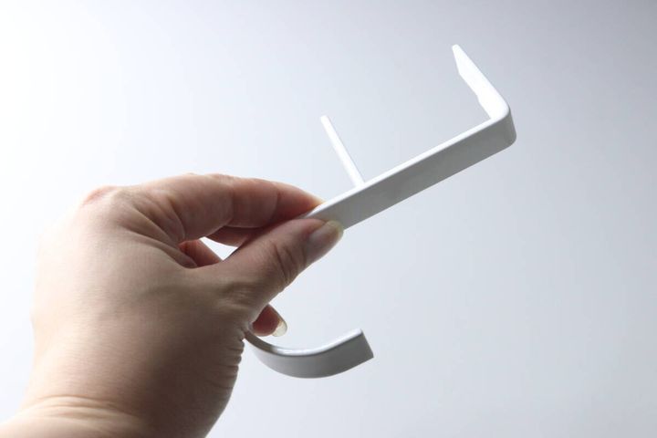 白い背景で、白いテーブルフック本体を片手で持っている