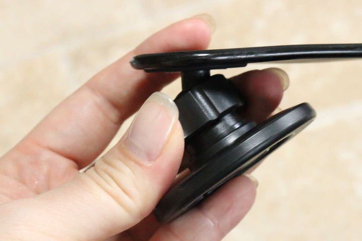 女性の手が車載スマホホルダーのヘッド部分を回して角度を調整している