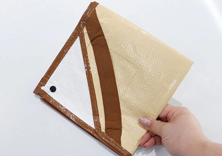 女性の手がベージュと茶色の折りたたまれたシートを持っている