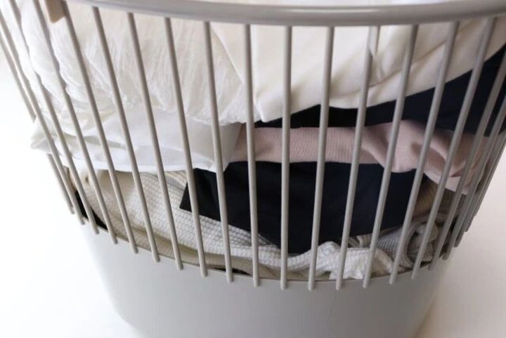 白いワイヤーバスケットの中に、たたまれた洗濯物や衣類がたっぷり入っている