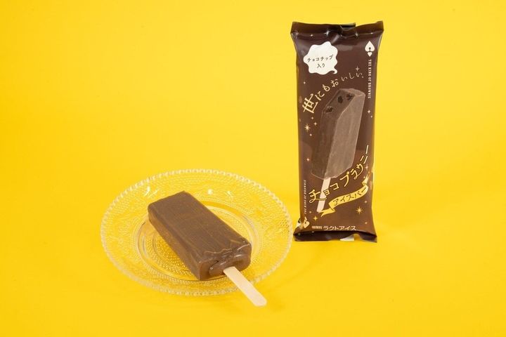 黄色い背景のガラス皿に置かれたチョコブラウニーアイスバーと袋
