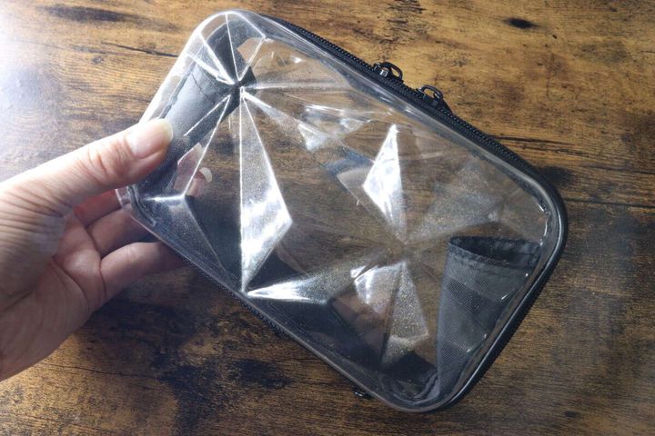 女性の手が透明なダイヤモンド形収納バッグを斜めから持っている