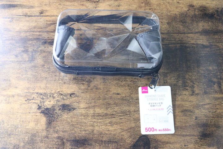透明なダイヤモンド形収納バッグと商品タグが木目のテーブルに置かれている