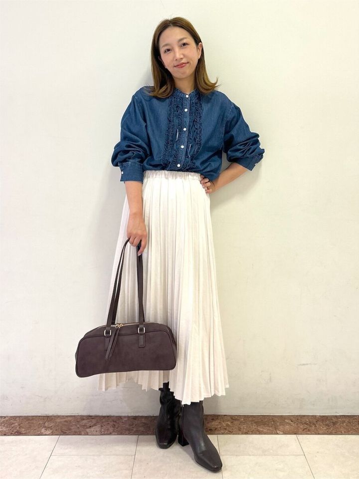 フリルデニムシャツと白プリーツスカートを着用した女性の全身