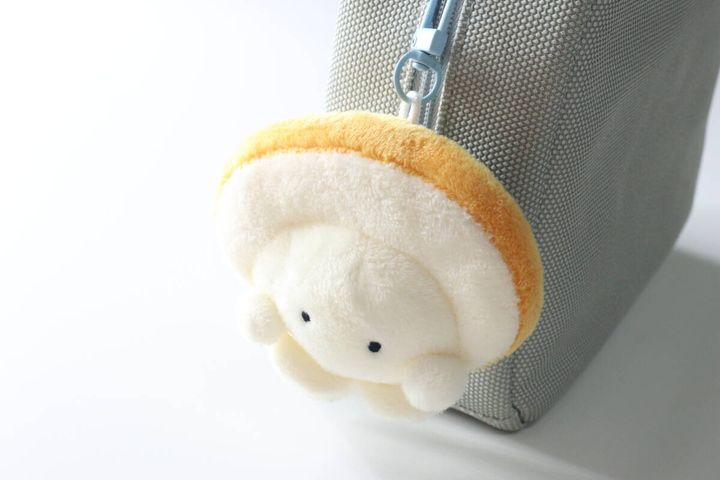 グレーのバッグのファスナーに付けられた求心フレンズのほたてぬいぐるみキーホルダー