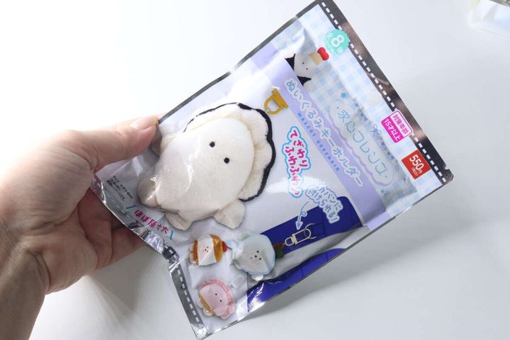 女性の手が求心フレンズぬいぐるみキーホルダーのパッケージを持っている様子