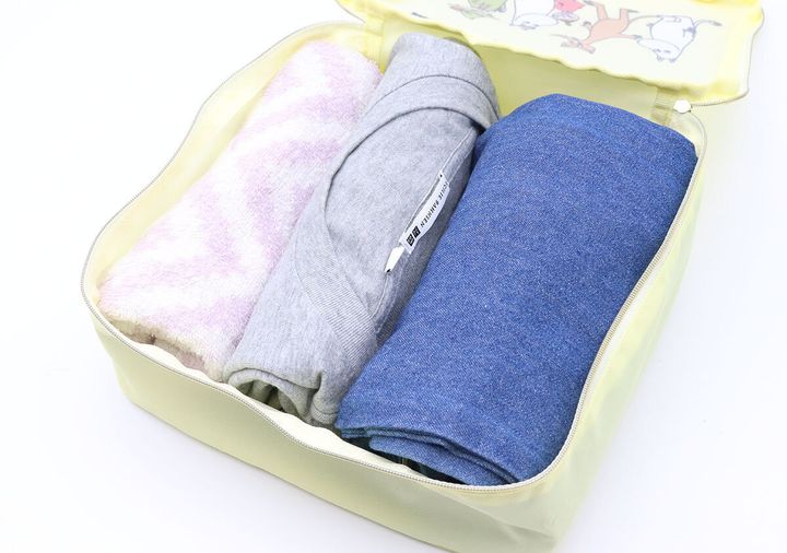 黄色い収納ポーチの中に、丸めたタオル、グレーのTシャツ、デニムパンツが収納されている