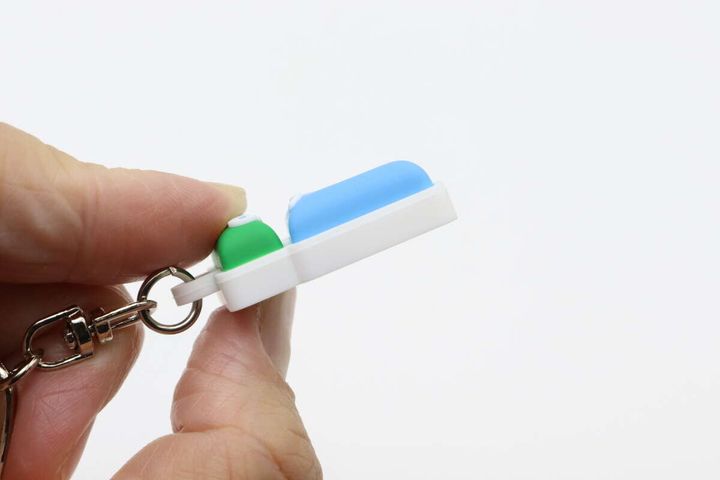 指でF MINIキーホルダーの厚みを確認している